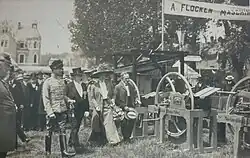 The Duke and Duchess of Saxe-Coburg and Gotha with two other men walking towards an outdoor display of agricultural equipment