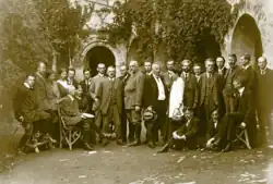 A group of men and women standing outside, with some seated in the front.