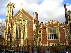 a pair of very old, red and white brick buildings. The one on the left is larger than that on the right and has a small tower. The buildings feature large stained glass windows on the front.