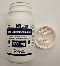 A bottle of lithium carbonate capsules with the cap off. Inside the cap are four lithium carbonate 300 mg pills.