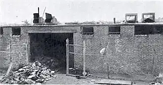 A pile of metal cans outside a fire-damaged brick building