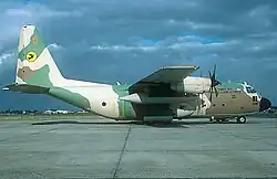 Colour photo of a C-130E camouflage coloured military plane with Yellow Bird Squadron symbol on the tail.