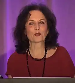 Tightly cropped headshot photo of Louise Fili in a maroon dress looking directly ahead speaking at a conference