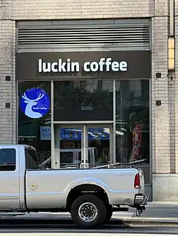 The side of a tan brick building with a Luckin Coffee store