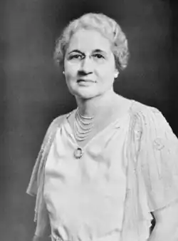 Photograph of a woman wearing a necklace and eyeglasses.