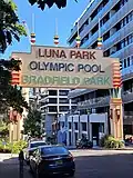 Large art deco sign over a street reading "LUNA PARK; OLYMPIC POOL; BRADFIELD PARK"