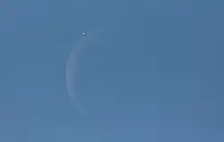 venus next to a crescent moon in the blue daytime sky