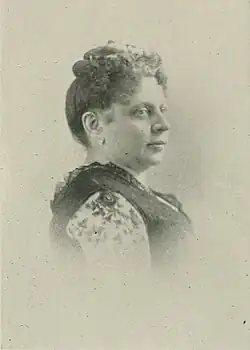 19th-century B&W portrait photo of a woman with her hair in an up-do, wearing a dark, fitted blouse.