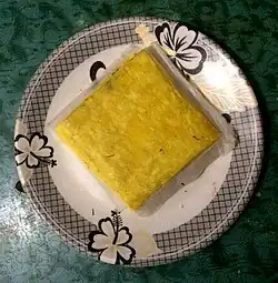 A square yellow sweet on a paper plate