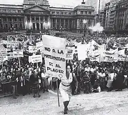 Image 6María Elena Oddone holding a banner, on International Women's Day in 1984 in Argentina. The banner says "No to motherhood, yes to pleasure" (from International Women's Day)
