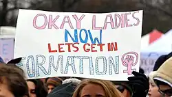 A poster with the song's lyrics and the feminism symbol