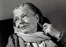 Photographie noir et blanc d'une veille femme aux yeux pétillants qui sourit.