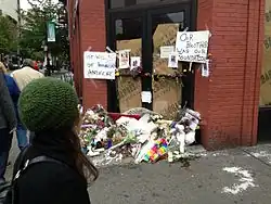 A color photograph of a sidewalk memorial for a man named Mark Carson