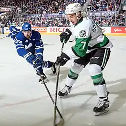 Ice hockey players in a Toronto Marlies jersey and a Texas Stars jersey skating with their sticks on the ice