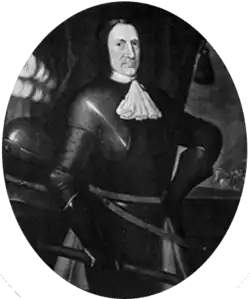 A black-and-white image of a stern-faced man in full early modern armour and a white neck ruff
