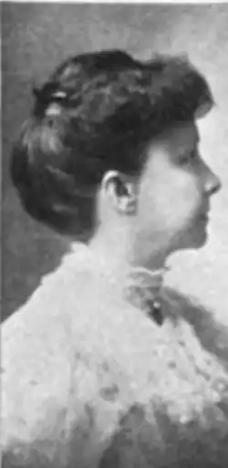 20th-century B&W portrait side view of a middle-aged white woman with her hair in an up-do, wearing a pale blouse with a frilly, high collar