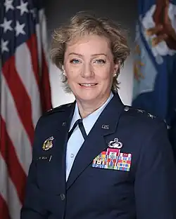 female dressed in military uniform in front of flag