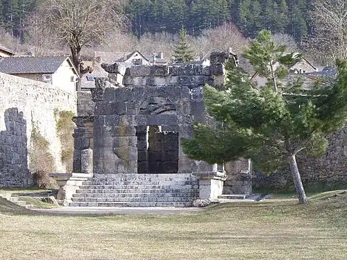 Color photograph of an old building in the background of a grassy area.