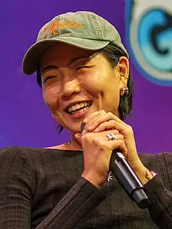 Closeup photo of May Hong. She is holding a microphone close to her face and looking off to her right, not directly toward the camera.