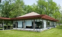 One-story building with large windows covered by white blinds and a red grid-like overhang