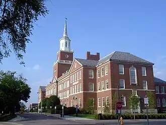 A large, red-brick building, with a prominent bell tower in the middle.
