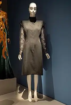 Knee-length black dress with arms of black lace, on a mannequin