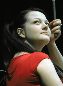 Meg White, holding a drumstick, glancing upwards to her right