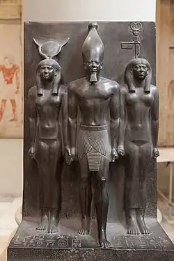 Statue of Menkaure with Hathor and Cynopolis; 2551–2523&nbsp;BC; schist; height: 95.5&nbsp;cm; Egyptian Museum (Cairo). Demonstrates a group statue with Old Kingdom features and proportions.[37]