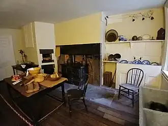 The kitchen, which has a fireplace mantel and various pieces of cookware
