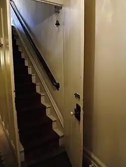 The hallway on the eastern side of the basement. There is a hallway between the front and rear sections; beyond it is a stairway.