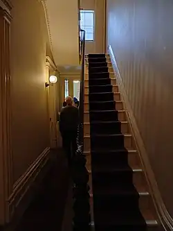 The hallway on the eastern side of the first floor. There is a stairway to the right.