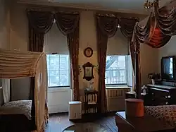 The rear second-floor bedroom, which has a canopied bed at right and a canopied crib at left