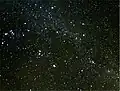 The brightest meteor, a fireball, leaves a persistent smoky trail drifting in high-altitude winds, which is seen on the right side of the image.