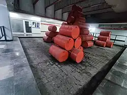 Picture of a reddish sculpture made of oil drums.