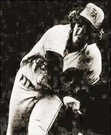 A man in a throwing motion delivery with a glove on his left hand