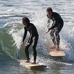 Two teenage surfers wearing wetsuits