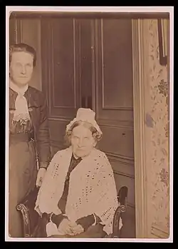 Two women, one sat and one stood alongside.