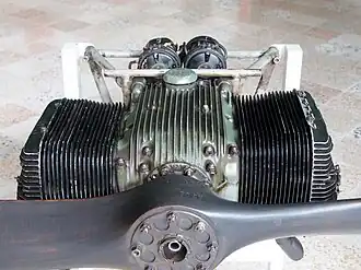 A small propeller-equipped aircraft engine on a stand, viewed from the front.