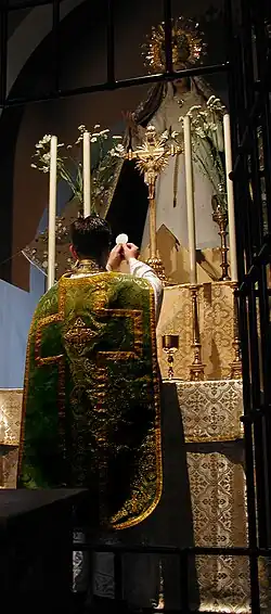 Catholic Priest elevating the Host (action incomplete)