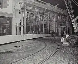 A large beam being lifted into place on the facade of an urban building