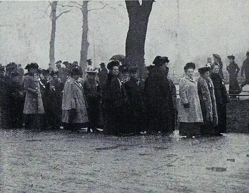 A group of marchers stand waiting in the rain.