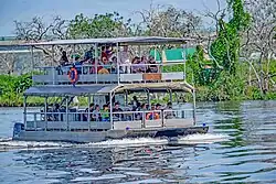A boat on river. In the boat are about 20 people.