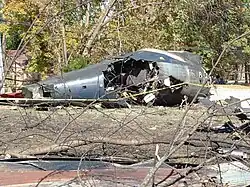 Wreckage of a burnt-out and charred aircraft aft fuselage on a residential road