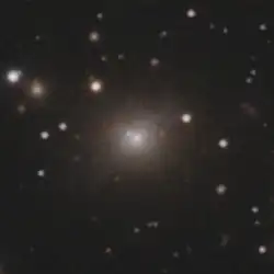 A grainy close up of the most prominent galaxy in the previous image. Faint white and red streaks are visible in front of it.