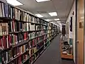 A shelf of books extends from the left to right along a carpeted hallway.