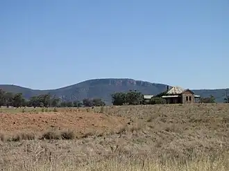 An abandoned homestead at Murga in front of the cliffs of Nangar National Park, as seen from the Escort Way