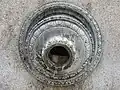 Circular opening finely sculpted; water flows out.