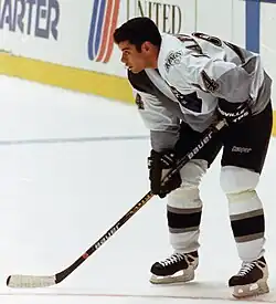 hockey player in white jersey holding hockey stick.