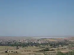 A town with red roofs near a body of water under a blue sky.
