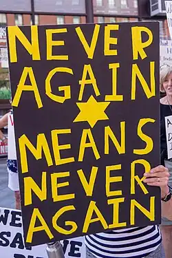 Yellow star and "Never Again Means Never Again" at a protest about immigration detention (2019)